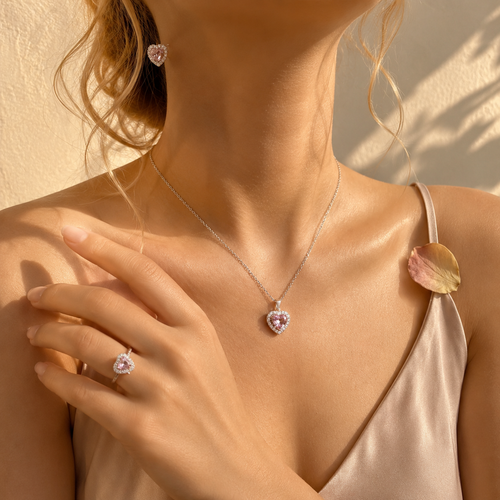 Set Trilogía Corazón de Cristal puesto: collar, anillo y aretes de corazón rosa, luz cálida